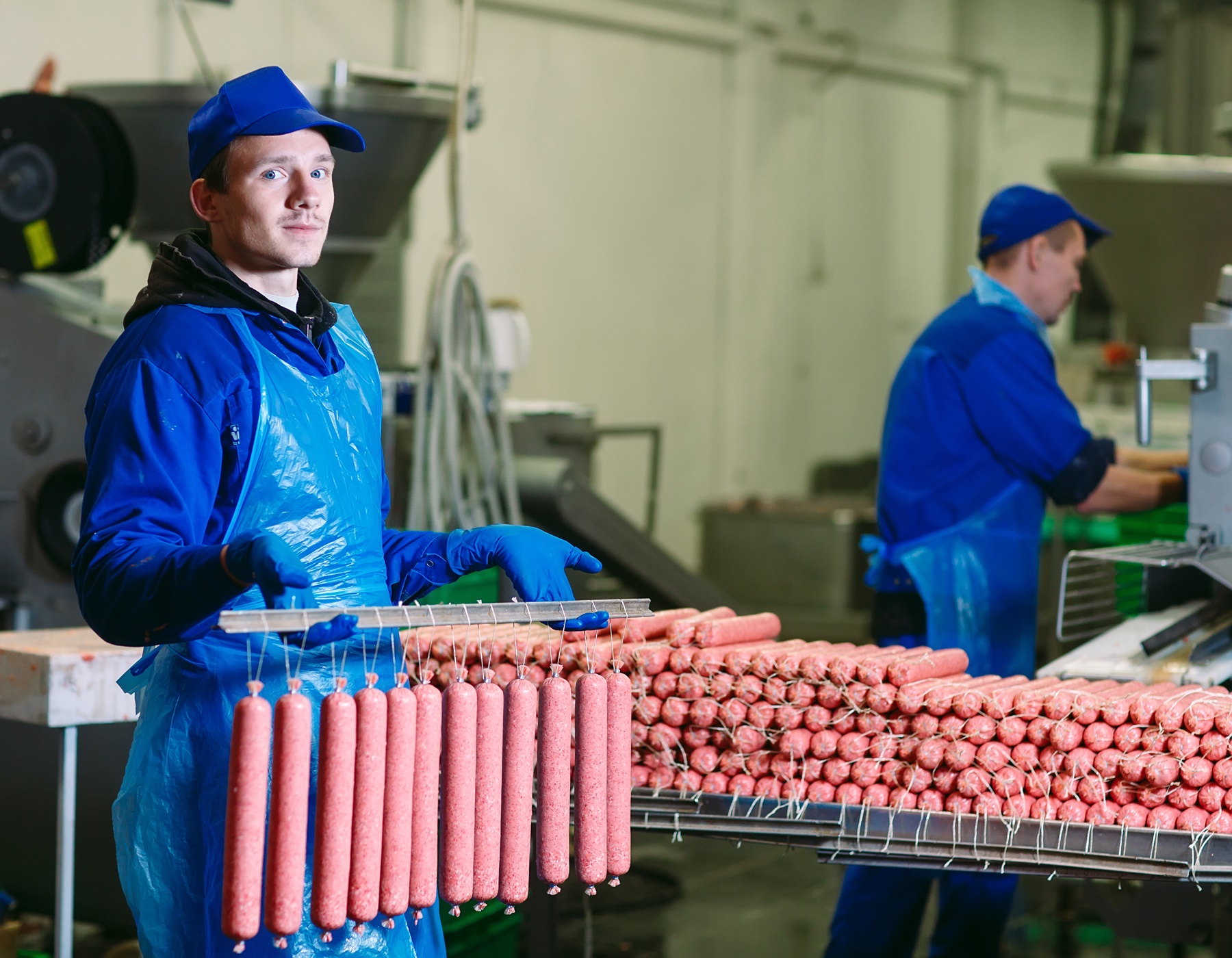 Butchers processing sausages at a meat factory.